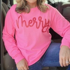Long sleeve shirt pink shirt with red merry writing.
